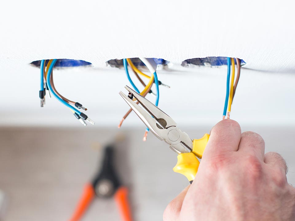 Electrician wiring ceiling cables during a residential electrical job in Canberra